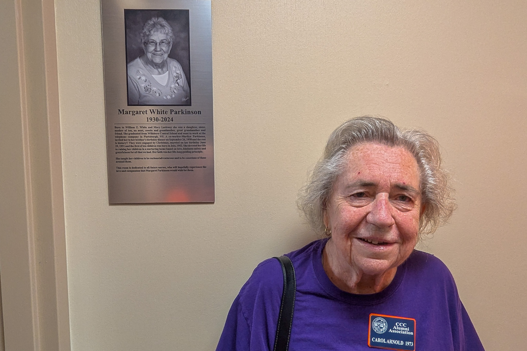 A woman stands next to a plaque on a wall