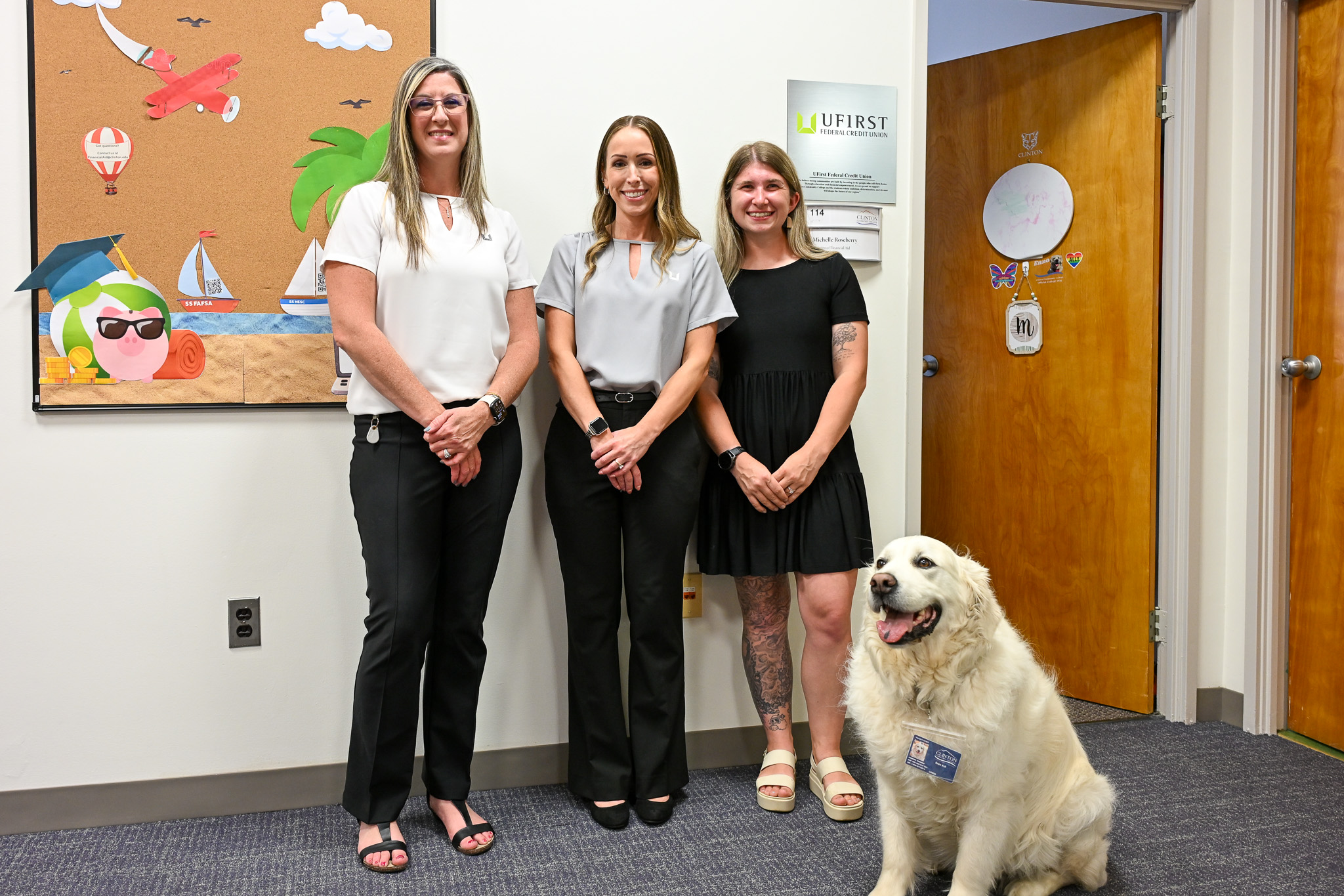 Three people standing in front of a wall with a dog sitting nearby